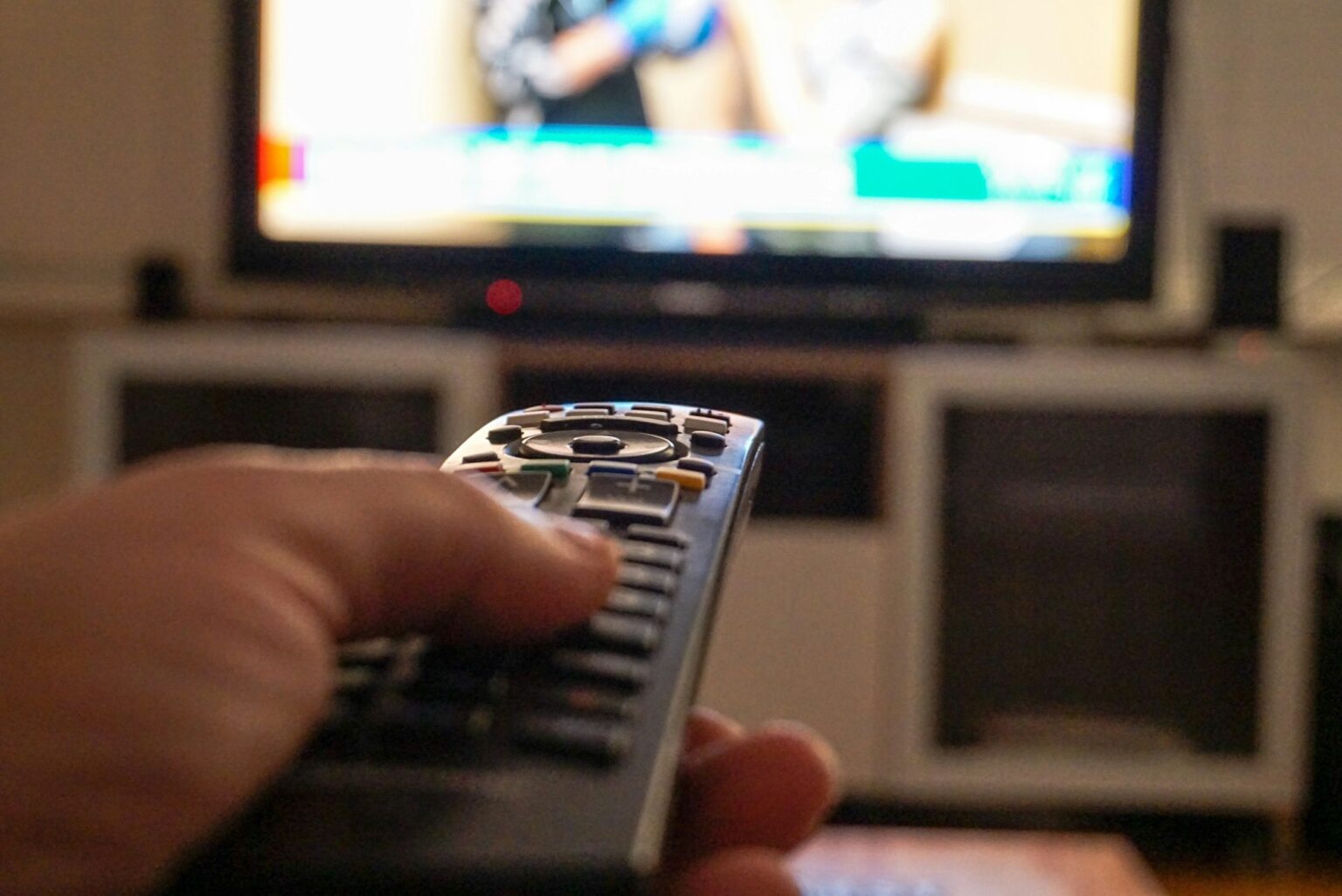 Comment regarder TF1 (TF1+) depuis l’étranger ? Hand holding a tv remote control while watching tv