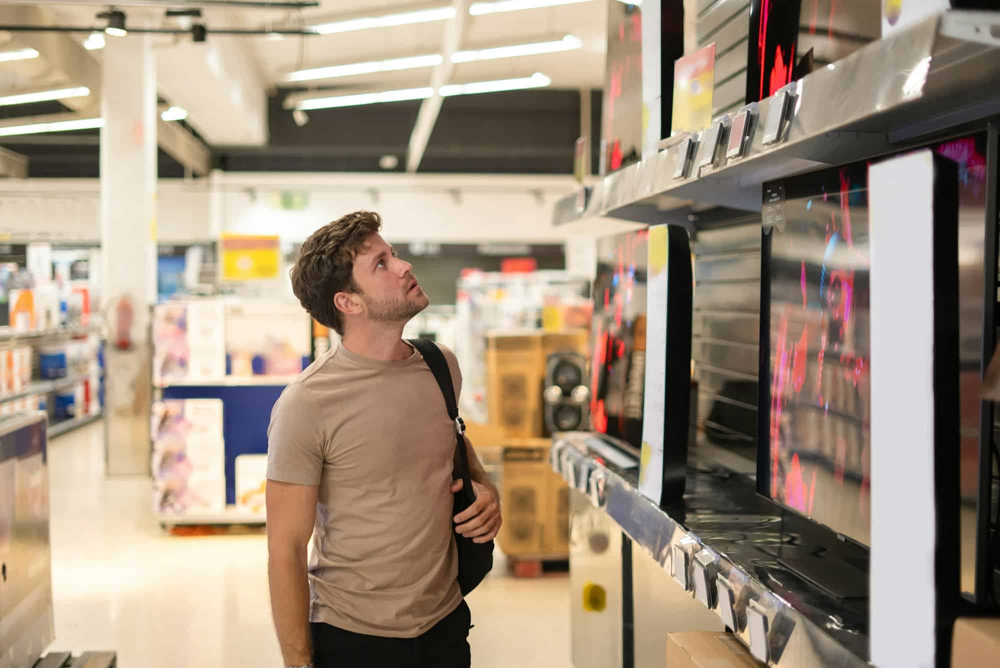 Male shopper examining TV on shelf