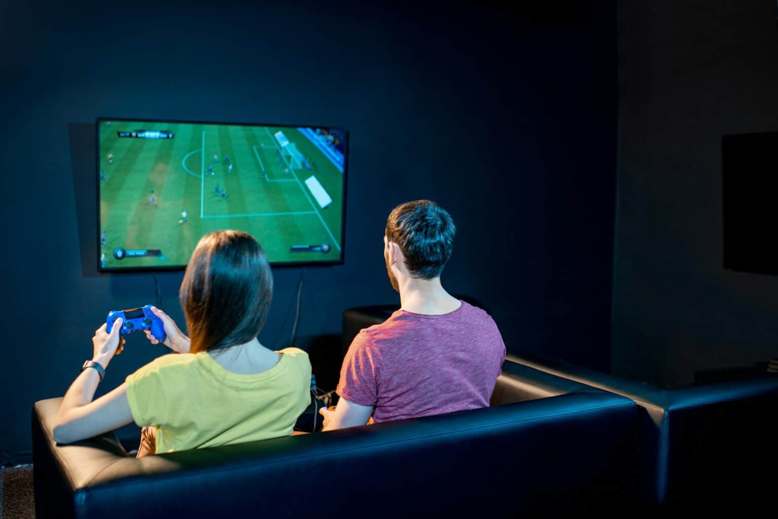 Faut-il (vraiment) acheter EA Sports FC 25 (anciennement FIFA) ? Couple playing football game with gaming console