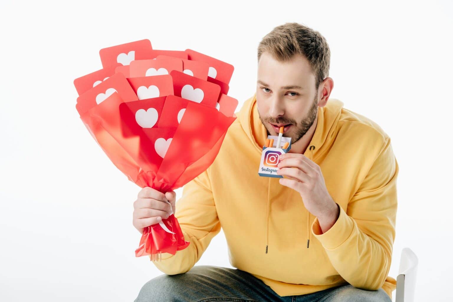 handsome man holding cigarette pack with instagram logo and bouquet of red paper cut cards with