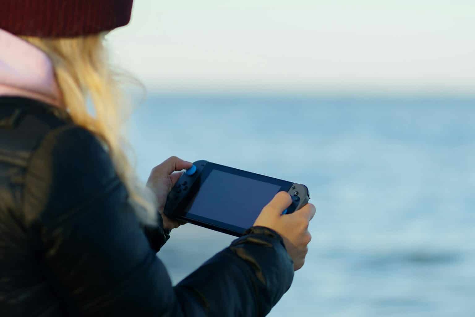 Coin Master : le jeu à succès qui passionne la France a woman holding a game controller in front of a body of water