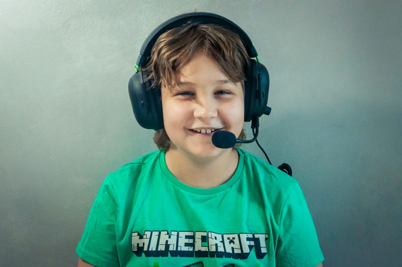 Comment créer un serveur Minecraft : le guide et la meilleure config A young boy wearing headphones and a green shirt