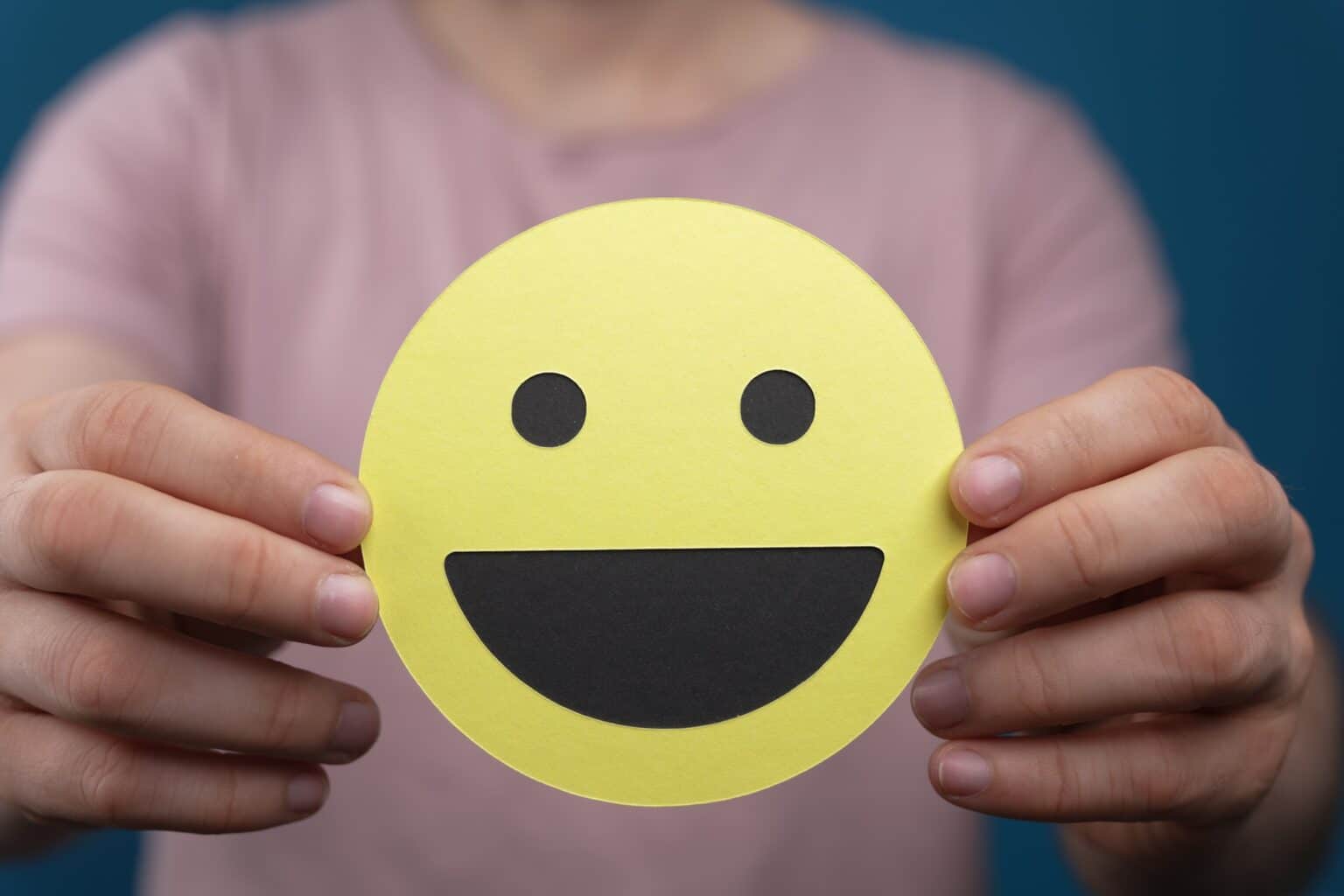Closeup of the smiley face emoji held by a person
