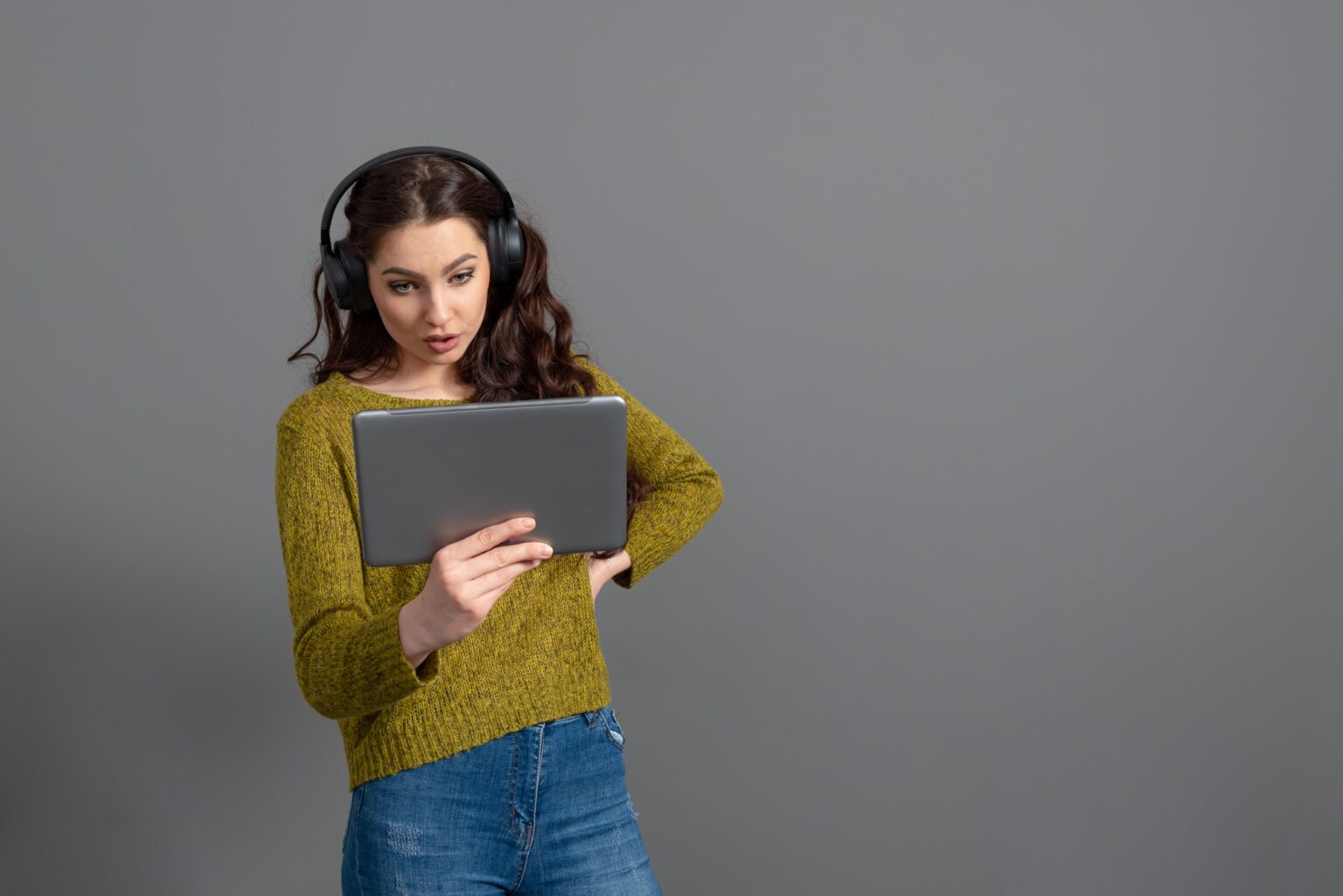young woman with headset and tablet in hand playing games and talking to friends online