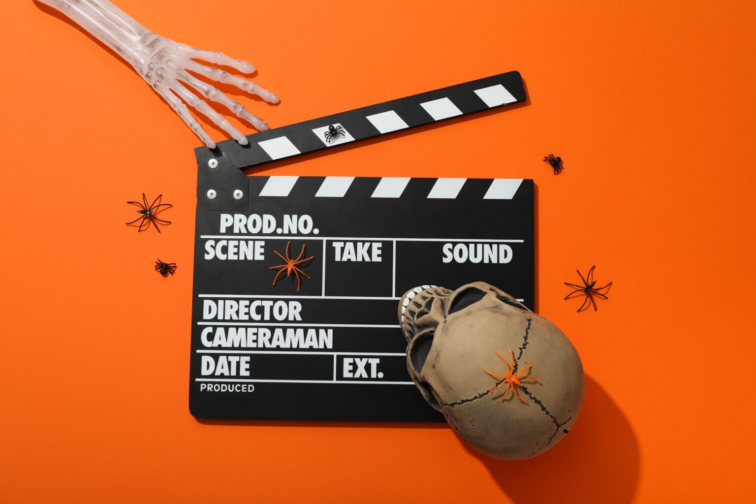 TOP 100 des films d’horreurs les plus effrayants selon le score de peur Clapperboard and Halloween decorations on orange background, top view