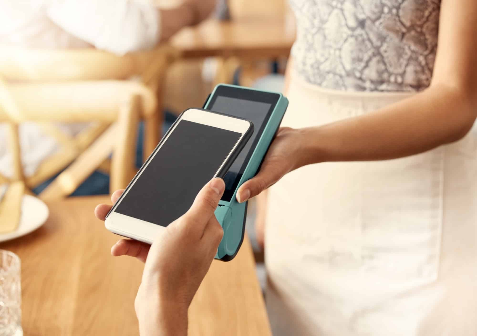Shot of a customer making a payment using their smartphone and a nfc machine