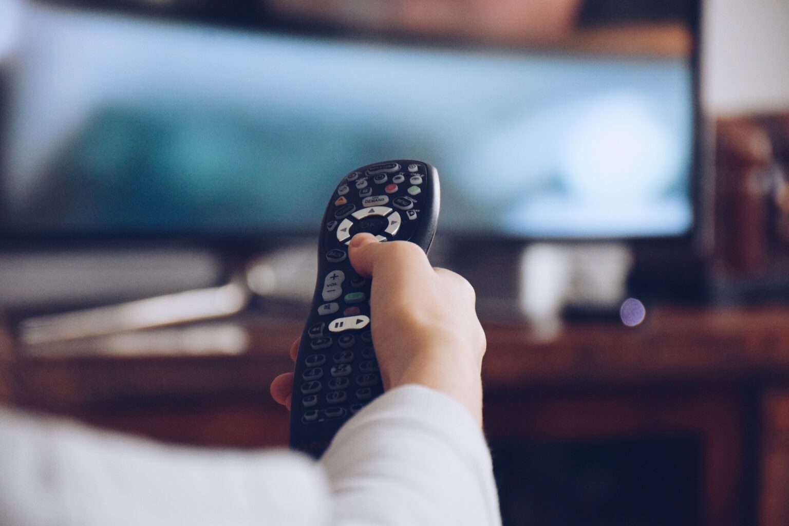 Molotov TV : accédez à plus de 50 chaînes de la TNT et services de replay Young girl holding a remote to flip channels on a TV