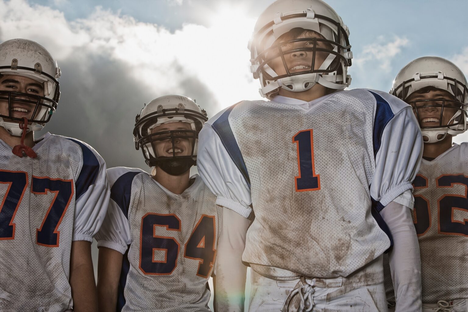 A group of football players, in uniform and helmets